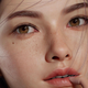 A virtual woman with purple hair and hazel eyes stares directly into the camera with a wistful expression on her face.